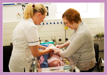 Photo of mother and nurse dressing a premature child.